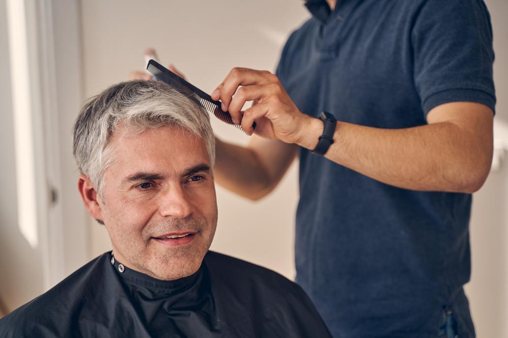 hair coloring is a growing trend in Indianapolis Men's Styling image shows man getting hair combed at salon