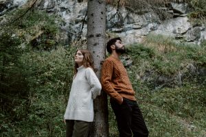 Personal Image Consultant Beth Divine stresses quality and fit when selecting a high-quality sweater. Image shows man in sweater leaning against tree next to woman.