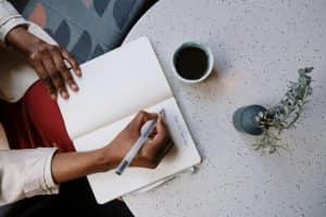 Planning your clothes is one idea for smart travel packing from Personal Image Consultant Beth Divine image shows person writing plan on paper