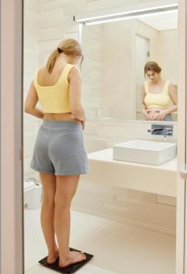 Work with Indianapolis Image Consultant Beth Divine to navigate style during weight loss image shows woman standing on scale in bathroom